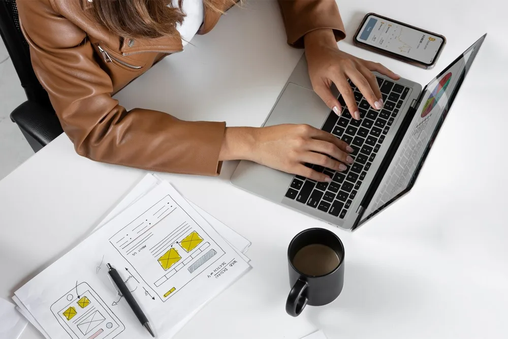 woman typing on a laptop with a cup of tea on table jpg.webp